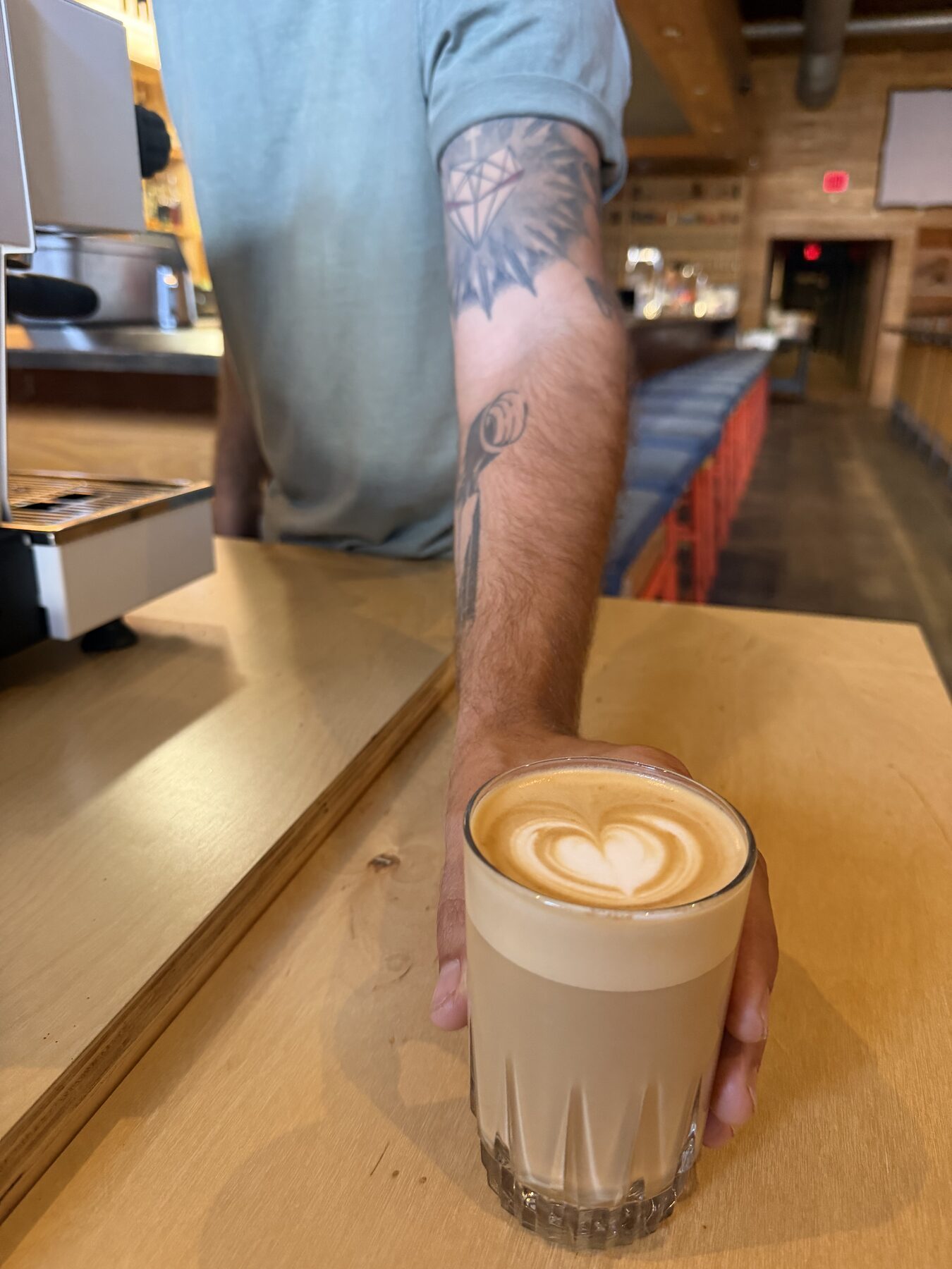 Barista handing a latte with heart art across the cart