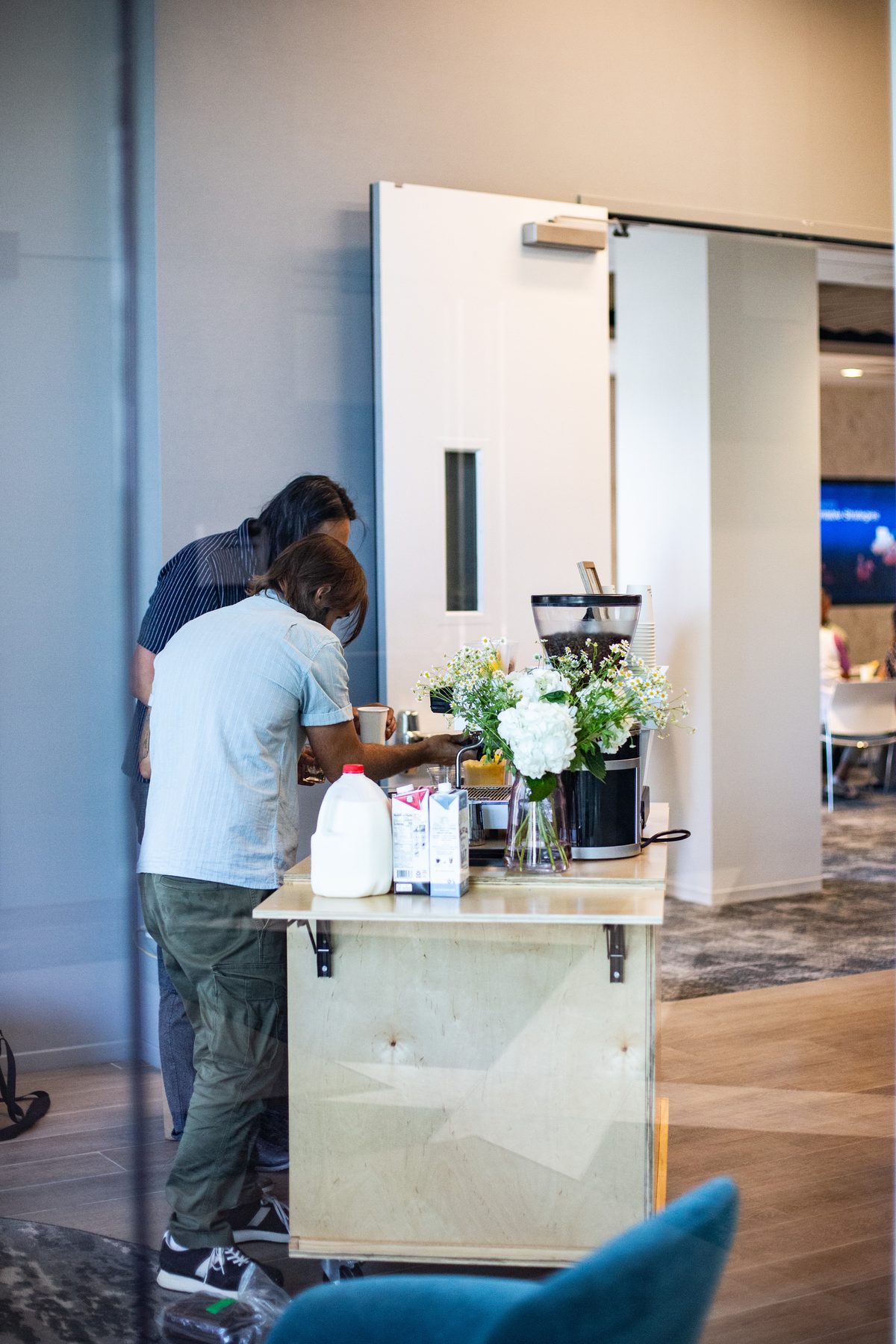 Two baristas setting up the coffee cart with flowers and milk before service